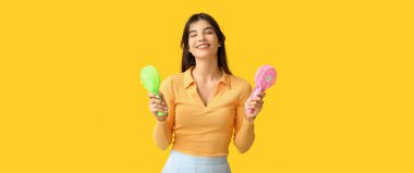 Sarı arka planda mini fanları olan genç bir kadın.