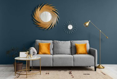 Oturma odasının iç tarafında yastıkları ve kahve masası olan rahat gri bir kanepe.