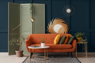 Yastıklı rahat bir kanepe, dergisi olan bir sehpa ve oturma odasında bitki.