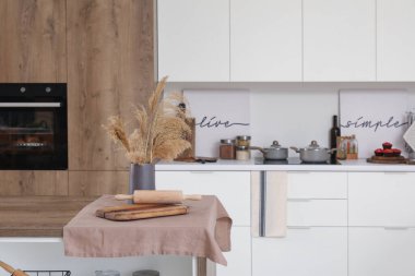 Çimenli vazo, tahta kesme ve modern mutfakta ada masasında merdane.