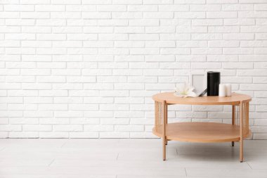 Boş cenaze çerçevesi, morg vazosu, mumlar ve nilüfer çiçekleri açık tuğla duvarın yanındaki ahşap masada.