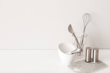Mutfak gereçleri beyaz duvarın yanındaki masada.