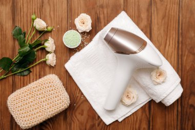 Banyo malzemeleri, deniz tuzu ve kahverengi ahşap arka planda güzel çiçekler olan modern fotoepilatör.
