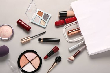 Gri arka planda makyaj malzemesi olan alışveriş torbası.