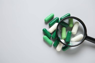 Gri arka planda farklı haplar içeren büyüteç