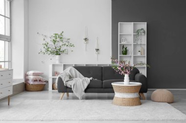 Oturma odasının şık bir iç mekanı. Kanepesi ve çiçek açan dalları olan kahve masası.