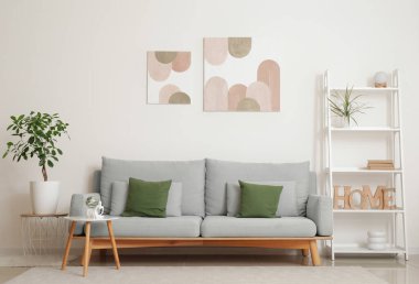 Rahat kanepesi, raf ünitesi, sehpası ve beyaz duvarlı resimleri olan şık bir oturma odası.