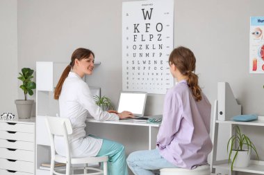 Dizüstü bilgisayarı olan kadın göz doktoru ve klinikte çalışan hasta.