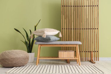 Güzel bir oturma odası, rahat bir bank, ev bitkisi, yastıklar ve katlanır ekran.