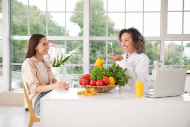 Ofiste müşteriyle çalışan olgun bir kadın beslenme uzmanı.