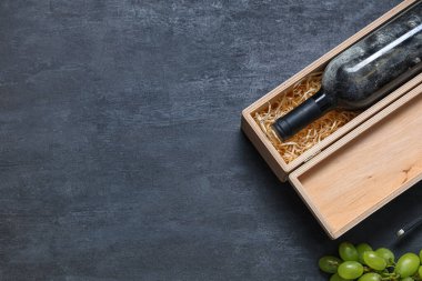 Siyah grunge arka planda şarap ve üzüm dolu bir kutu.