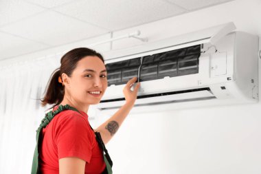 Kadın teknisyen evde klima tamir ediyor.