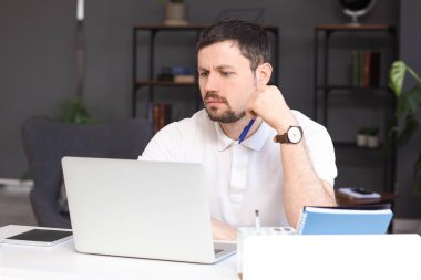 Evde online ders veren kafası karışmış bir erkek öğretmen.