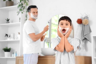 Babası ve köpüklü küçük oğlu banyoda tıraş oluyor.