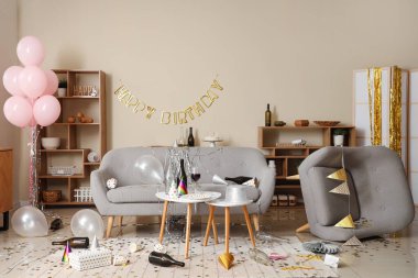 Doğum günü kutlamasından sonra kanepe, koltuk ve parti dekoruyla dağınık oturma odasının içi.
