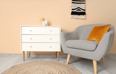 Bej duvarın yanında rahat koltuğu ve klozeti olan modern odanın içi.