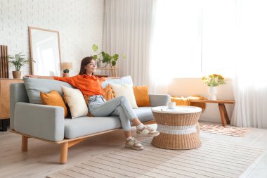 evde koltukta oturan genç ve güzel kadın