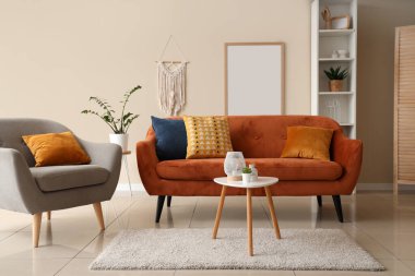 Oturma odasının içinde kırmızı kanepe, koltuk ve boş çerçeve.