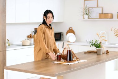 Lezzetli bir sürahi kvass, ekmek dilimleri ve mutfakta dikenleri olan genç bir kadın.