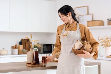 Bir bardak lezzetli kvass, ekmek somunları ve dikenli dikenleri olan genç bir kadın.