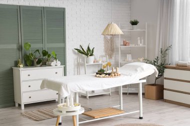 Masaj koltuğu, raf ünitesi ve bitkileri olan bir kaplıca salonu.