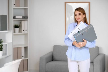 Ofisinde evrak klasörleri olan genç bir iş kadını.