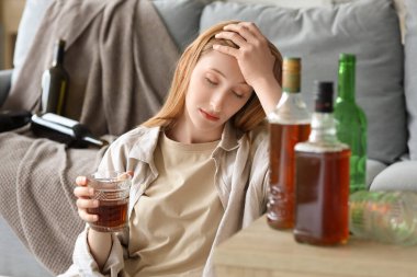 Evde alkol alan genç bir kadın. Alkolizm kavramı