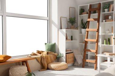 Oturma odasının içinde kitap, çiçek ve kanepe olan raf ünitesi.