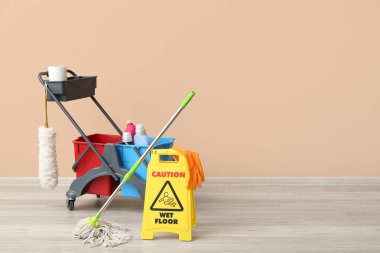 Kapıcının arabası ve uyarısı bej duvarın yanında.