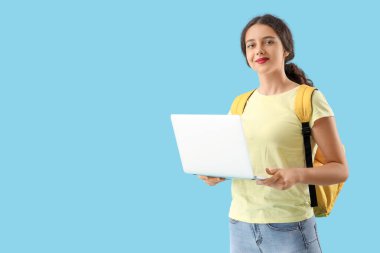 Mavi arka planda dizüstü bilgisayarı olan bir kız öğrenci.