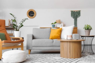 Ayna, gri kanepe ve koltuklu aydınlık oturma odasının içi.