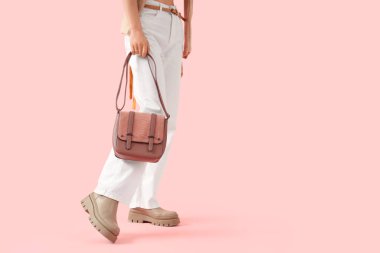 Pembe arka planda şık çantalı güzel genç bayan, yakın plan.