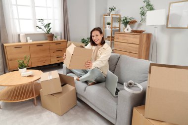 Güzel, genç, mutlu bir kadın. Evde bir sürü koli var.