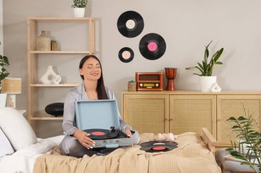 Yatak odasında pikabı olan genç bir kadın oturuyor.