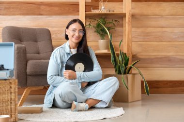 Plak çalar için vinil diski olan güzel bir kadın evde oturuyor.