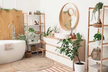 Çekmeceleri, küveti, çiçekleri ve raf ünitesi olan güzel bir banyo.