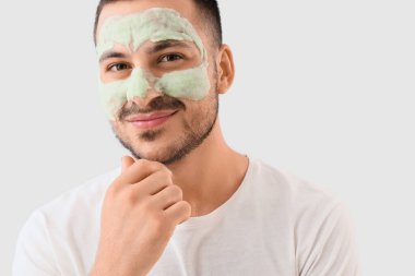 Yüzünde kozmetik balon maskesi olan yakışıklı, düşünceli genç bir adam.