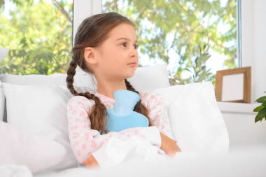 Yatak odasında sıcak su şişesi olan hasta küçük kız.