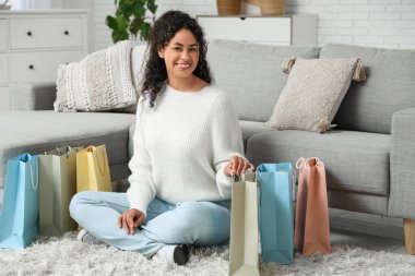 Evinde alışveriş torbaları olan mutlu Afro-Amerikan kadın.