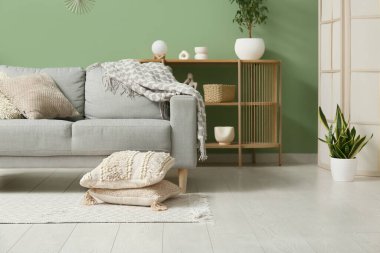 Şık oturma odasında yumuşak yastıklı gri kanepe.