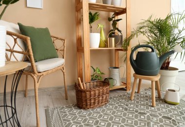 İçinde yeşil bitkiler, koltuk ve raf ünitesi olan bir oda.