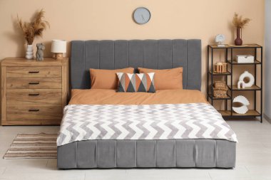 Şık bir yatak odası, rahat bir yatak odası, çekmeceler ve vazo dolusu otlar.