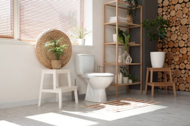 Tuvaletin içinde klozet, raf ünitesi ve bitkiler var.