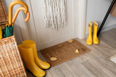 Koridorda sonbahar yaprakları ve çizmeleri olan kapı paspası