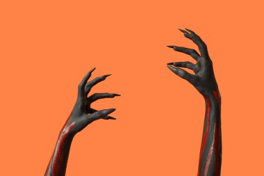 Turuncu arka planda pençeleri olan kara cadı elleri. Cadılar Bayramı