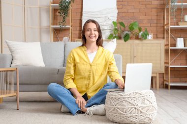 Pouf 'un evinde dizüstü bilgisayar kullanan genç bir kadın.