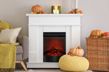 İçinde şömine, sonbahar dekorasyonu ve puf olan ışık odası.