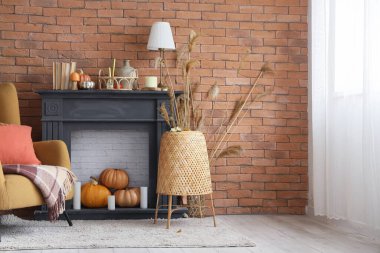 Şömine, yumuşak koltuk, ekose, lamba ve balkabakları sonbahar oturma odasında.