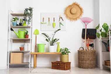 Tahtası, bahçe aletleri ve ahır beyaz duvarın yanında bitkileri olan işyeri