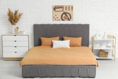 Şık bir yatak odası, yatak odası, çekmeceler, raf ünitesi ve vazo dolusu otlar.